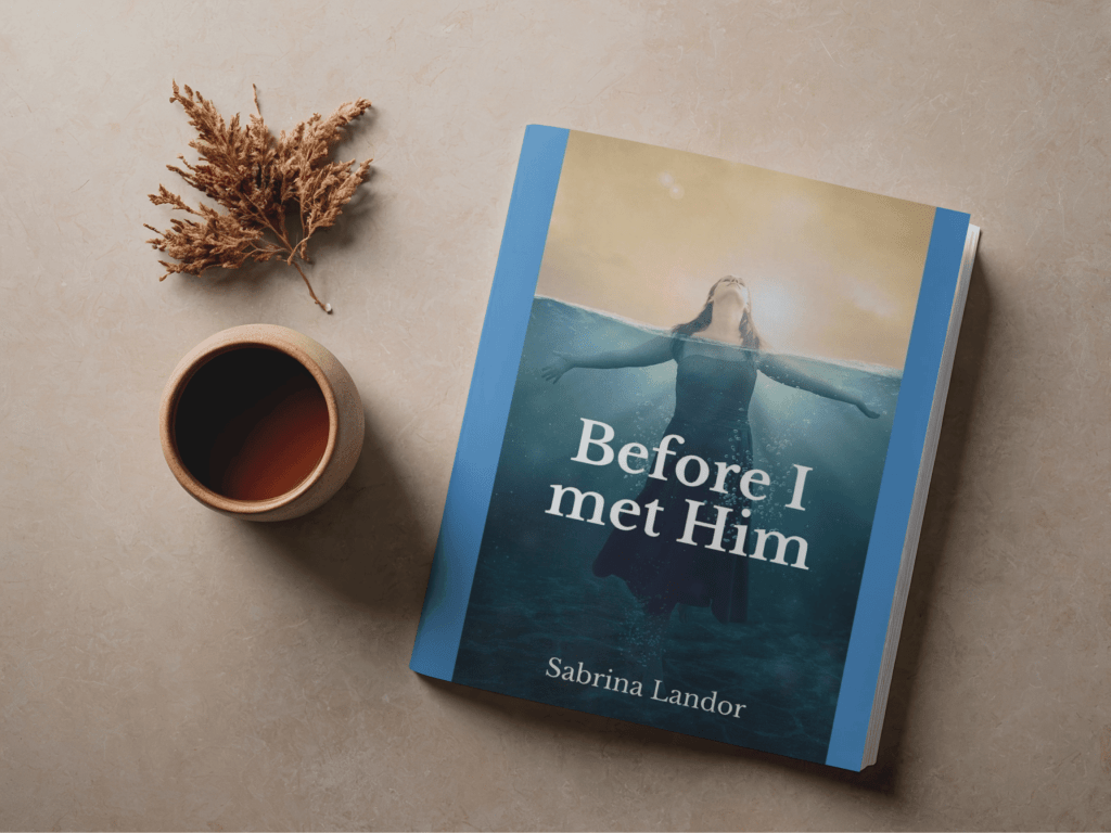 A book titled "Before I Met Him" by Sabrina Landor lies on a beige surface. The cover depicts a woman immersed in water, arms outstretched. A cup of tea and dried leaves rest nearby, creating a calming, introspective mood.
